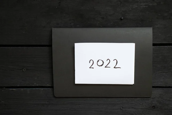 黑色笔记本 白纸写着2022年黑色木制桌子上的文字 白纸上写着2022年 新年快乐 — 图库照片