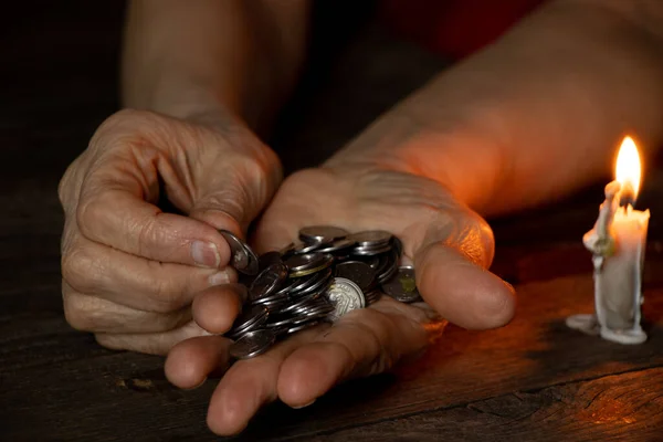 hands of an old woman with pennies on a table in the dark near a candle, money in the hands of a pensioner