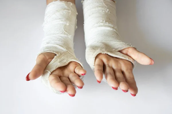two female hands with broken wrists after falling from a bicycle in a cast on an isolated background, hands in a cast