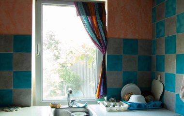 kitchen countertop with a set of clean washed dishes brought windows and sinks, kitchen table, plate on the shelf
