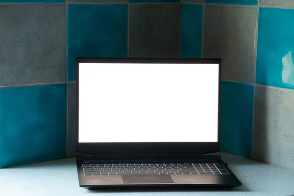 black laptop with white screen stands on the kitchen on the table at home, laptop with white screen, template, laptop on the table