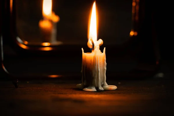 燃烧的蜡烛站在黑暗中靠近镜子的黑色木制桌子上 蜡烛在黑暗中燃烧 — 图库照片