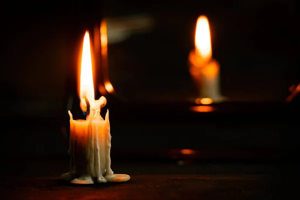 火のろうそくは鏡の近くの暗闇の中の黒い木製のテーブルの上に立ち闇の中のろうそくの火宗教 — ストック写真