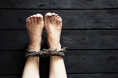 Siyah zeminde yaşlı bir kızın ipiyle bağlanmış bacak, insan ticareti, kölelik, vasiyet yok.