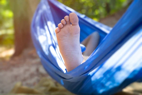 children\'s foot in a hammock, rolling in the forest in the summer in the sun, rest in a hammock, a foot in a hammock, rest in the forest