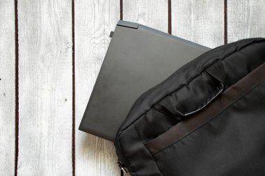 Siyah dizüstü bilgisayar ve siyah dizüstü bilgisayar çantası eski ahşap masada, dizüstü bilgisayar masada.