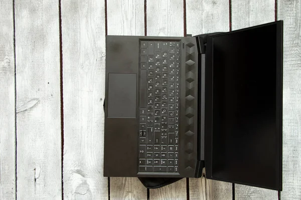 black laptop and black laptop bag lie on the written old wooden table, laptop on the table