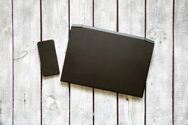 Schwarzer Laptop Und Telefon Liegen Auf Dem Beschriebenen Alten Holztisch — Stockfoto