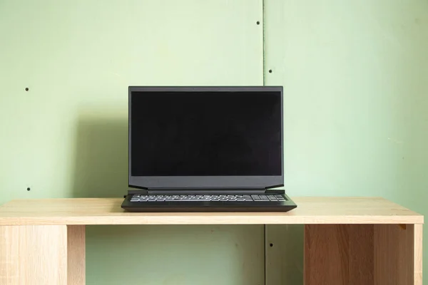 a black laptop with a black screen stands on a table in a room of a house with walls made of gypsum cardboard without repair, an old apartment is renovated, a laptop with a white screen