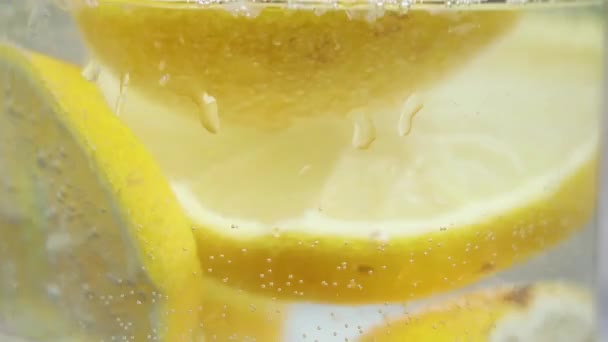 太陽の下のテーブルの上のガラスの輝く水の中のレモン レモンと水 飲み物 — ストック動画