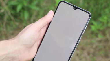 Telefon, sokaktaki bir kızın elinde. Güneşte, telefonla iletişim, telefon caddenin elinde.