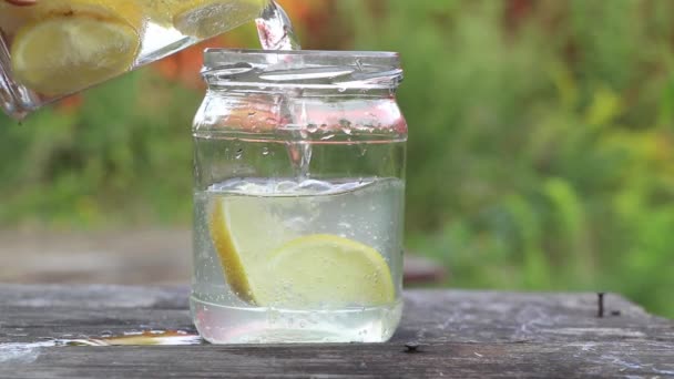 太陽の下のテーブルの上のガラスの輝く水の中のレモン レモンと水 飲み物 — ストック動画