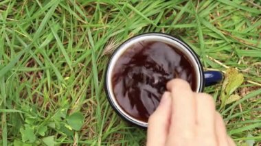 Açık yeşil çimen masasında bir fincan krema, çimlerin üzerinde bir fincan kahve.