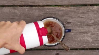 Dışardaki eski ahşap masada bir fincan kremalı kahve, masanın üstünde bir fincan deri.