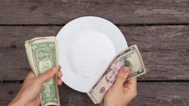 Tahta arka planda beyaz bir tabakta dolar, para saymak, para saymak, finans