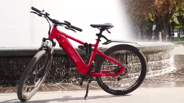ウクライナDnepr 2021 Himo C26レッド電動自転車は 太陽の下で都市噴水を上げる価値があります 電気輸送 公園内の都市で自転車 — ストック動画