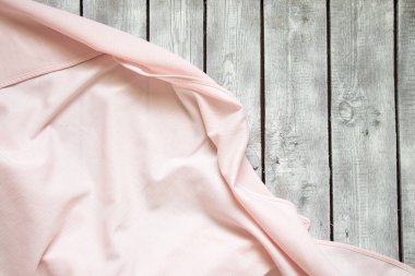 Pembe buruşuk masa örtüsü arka planda yakın plan olarak beyaz bir ahşap masada yatıyor.