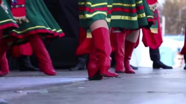 Geleneksel Ukrayna kostümlü kızlar ve yüksek kırmızı çizmeler sokakta dans ediyorlar, kırmızı kadın çizmeleri.
