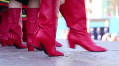 Geleneksel Ukrayna kostümlü kızlar ve yüksek kırmızı çizmeler sokakta dans ediyorlar, kırmızı kadın çizmeleri.