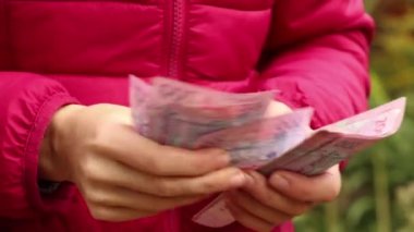 Kız, sokakta 200 UAH değerinde banknotlar düşünüyor. Ukrayna parası kızın elinde, 200 UAH.