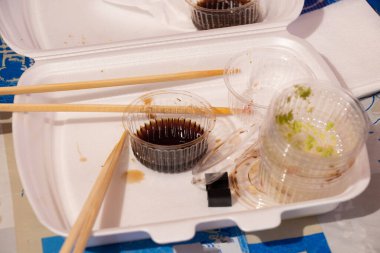 Akşam yemeği için plastik ambalajlı bir dükkandan suşi seti, evdeki masada suşi, plastik tek kullanımlık suşi paketi.