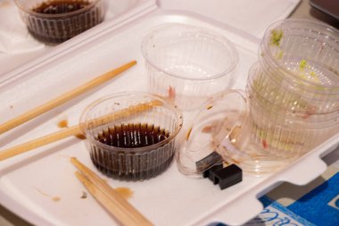 Akşam yemeği için plastik ambalajlı bir dükkandan suşi seti, evdeki masada suşi, plastik tek kullanımlık suşi paketi.