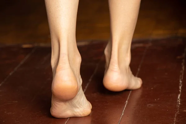 Дівчина стоїть босоніж на старій брудній дерев'яній підлозі будинку в кімнаті, жіночі ноги на підлозі — стокове фото