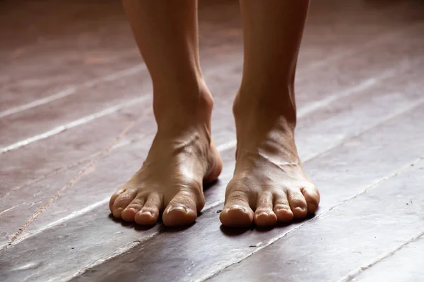 Fille debout pieds nus sur le vieux plancher de bois sale de la maison dans la chambre, pieds féminins sur le sol — Photo