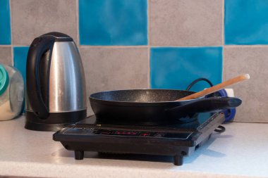 Kızartma tavası tek bir indüksiyon elektrikli ocağın üstünde. Dairedeki mutfak masasında, mutfakta, ocağın üstünde.