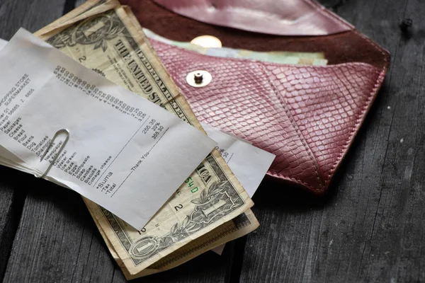 Un cheque del supermercado con dólares yace una tos con dinero en una mesa de madera en la luz en casa, dinero en la mesa —  Fotos de Stock