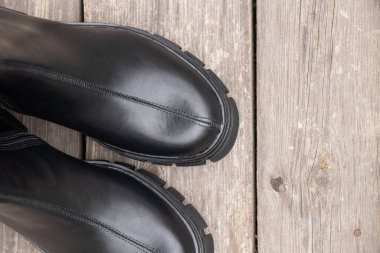 Siyah, yüksek tabanlı kadın çizmeleri sokağın eski tahtasında durur, kadınların kış ayakkabıları, ayakkabıları