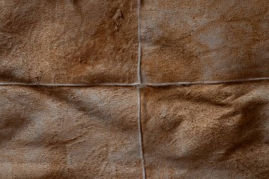 Görünür dikişleri olan kahverengi süet bir yüzeye yakın plan. Yumuşak süet dokusu arka plan olarak uygundur