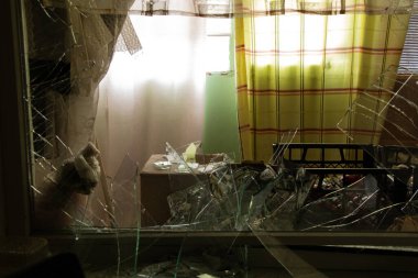 Ukrayna 'daki savaş sırasında camları kırık olan çok katlı bir binanın penceresinin altında bir İHA' nın patlaması sonucu yıkılan bir daire.
