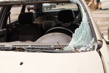 Ukrayna 'daki savaş sırasında bir yerleşim yerinin yakınındaki insansız hava aracının çarpması sonucu hasar gören bir araba.