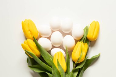Beyaz tavuk yumurtaları ve sarı laleler temalar için beyaz bir zemin üzerinde bulunur: Paskalya hazırlıkları, Paskalya yemeği malzemeleri
