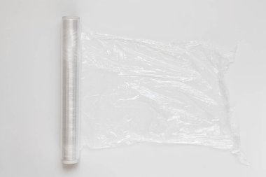 Yırtık kenarlı bir yapışkan film rulosu beyaz arka planda yatıyor.