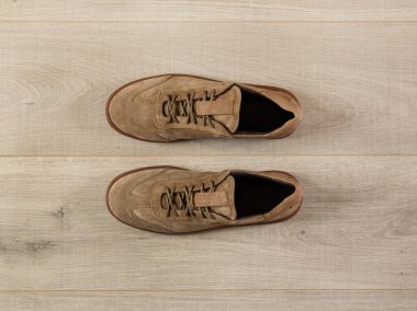 Bir tahta yüzeyin arka planında bir çift yumuşak süet spor ayakkabısı.