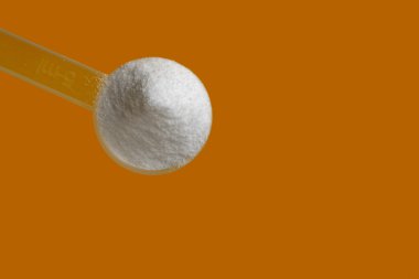 Creatine monohydrate in  scoop isolated on yellow background clipart