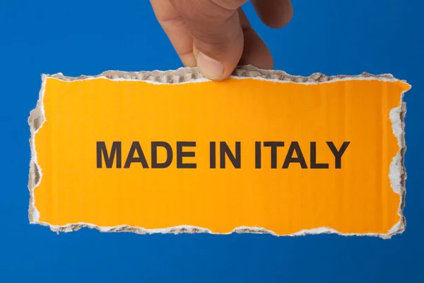 男人手里拿着一张撕破的纸 上面有意大利制造的蓝色背景的文字 — 图库照片