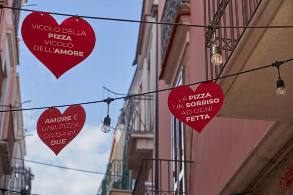 Romantic Italian alley decorated with red heart pizza signs, symbol of love, joy, and Italian food tradition