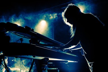 Girl playing keyboards during concert, silhouette with backlight clipart