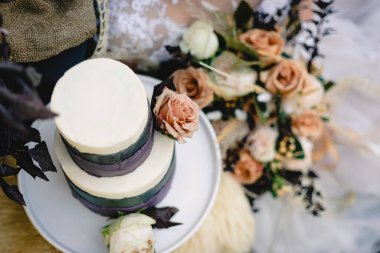 Açık pembe güllü düğün pastası, kırsal kesime karşı mor ganache.