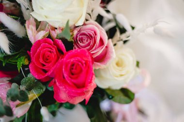 Gelin güzel, canlı bir buket beyaz ve pembe gül tutuyor.