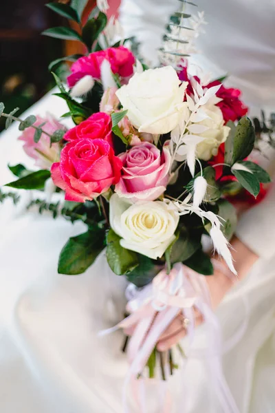 Gelin güzel, canlı bir buket beyaz ve pembe gül tutuyor.