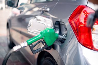 Benzin istasyonundaki adam yakıt deposuna hortum sokuyor ve benzin pompasını çalıştırıyor. Petrol pompasını kesiyor.