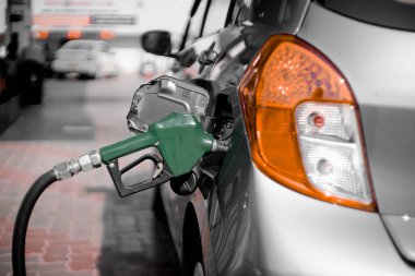 Benzin istasyonundaki adam yakıt deposuna hortum sokuyor ve benzin pompasını çalıştırıyor. Petrol pompasını kesiyor.