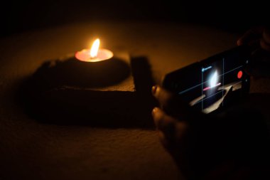 Hindu bayramı Diwali 'nin görüntülerini paylaşmak için cep telefonlu bir diya yağı lambasının düşük ışık resimlerini çeken erkek kadın.