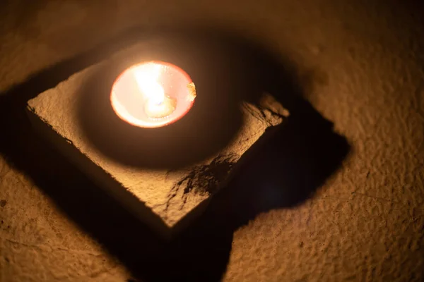 Foto de arriba hacia abajo mostrando una lámpara de aceite de diya llena de aceite y una mecha de algodón encendida colocada en una habitación oscura ahuyentando la oscuridad con su luz en el festival hindú de diwali dussera — Foto de Stock