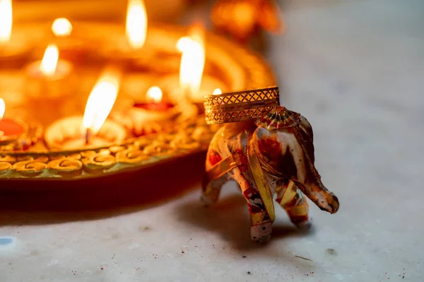 Elefante incensario con humo que sale de ella y hermosas lámparas de diya de loza pintadas de oro llenas de aceite y encendidas con una llama en el fondo — Foto de Stock