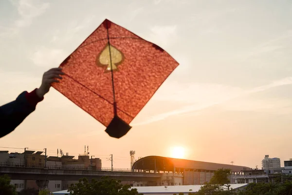 Jeune homme tenant en hauteur du papier coloré et cerf-volant en bois sur un fond flou coucher de soleil sur le festival indien de cerf-volant de makar sankranti ou uttarayana — Photo